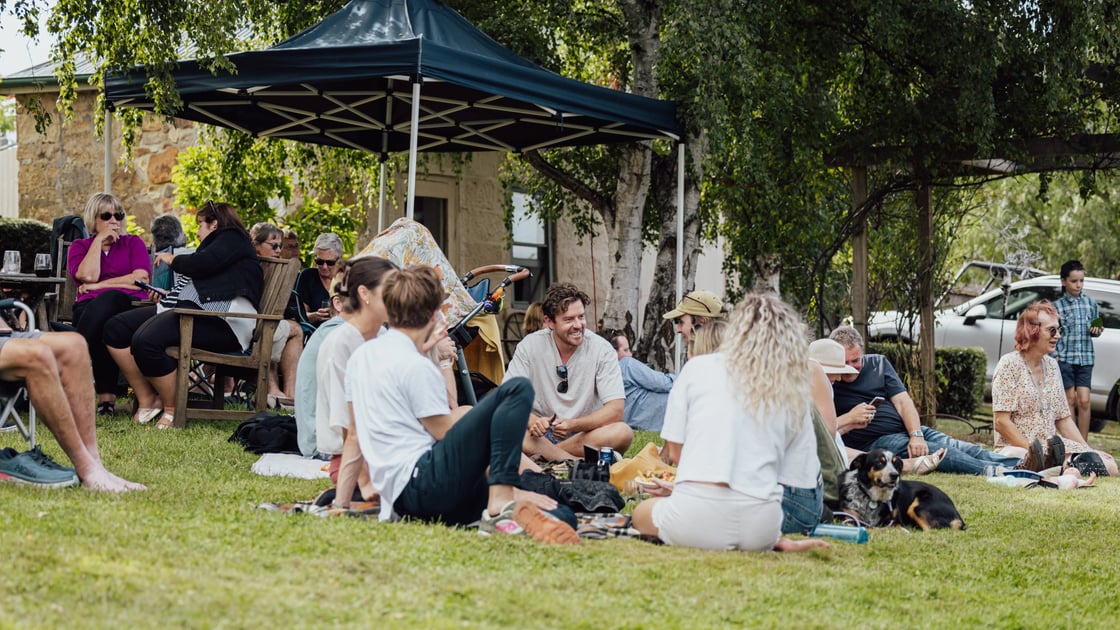 Uplands Vineyard, people sitting on a green lawn enjoying wine, food and music